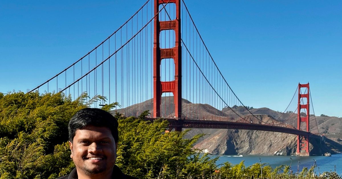 Dulan Dias smiling in front of the Golden Gate Bridge on a clear day